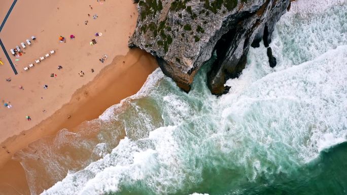 空中鸟瞰超现实的普拉亚达阿德拉加海滩在辛特拉，葡萄牙。白色的海浪卷向有着巨大悬崖的海滩。大西洋