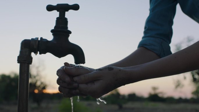 日落时分，农妇在自来水龙头下用清水洗手