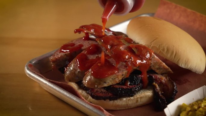 挤瓶的红色烧烤酱淋在香肠胸肉三明治上，慢动作近距离滑块4K