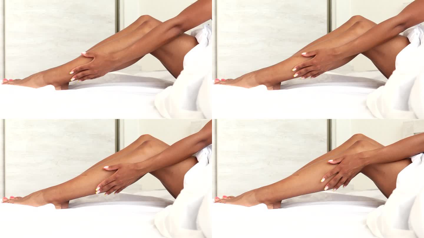 在床上脱毛后，美丽的黑人女性拥有完美健康柔滑的腿部皮肤。