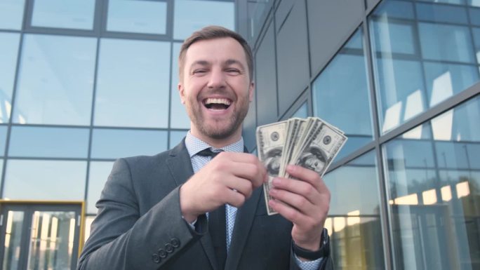 一个富人撒着钞票，对着镜头微笑。商业和金融概念。一个富人