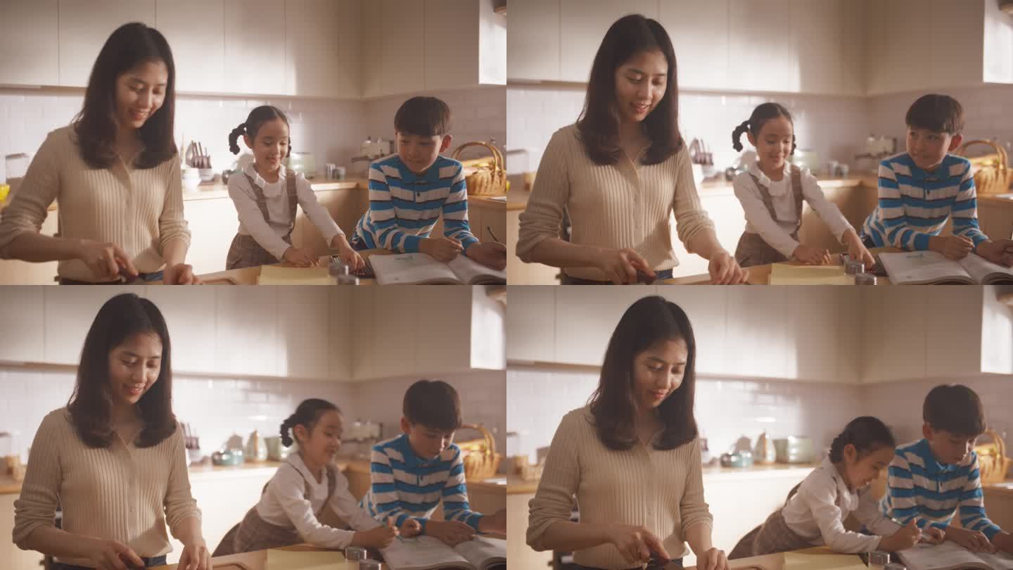韩国家庭在厨房里的照片:可爱的孩子们在妈妈准备午餐的时候陪伴着她。他们在画画和上色，而他们的妈妈正在