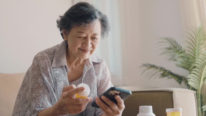 快乐的老妇人在家里用智能手机在线购买药品申请。