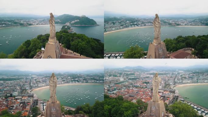 西班牙圣塞瓦斯蒂安基督雕像周围的空中视差轨道，俯瞰绿色海湾和金色沙滩