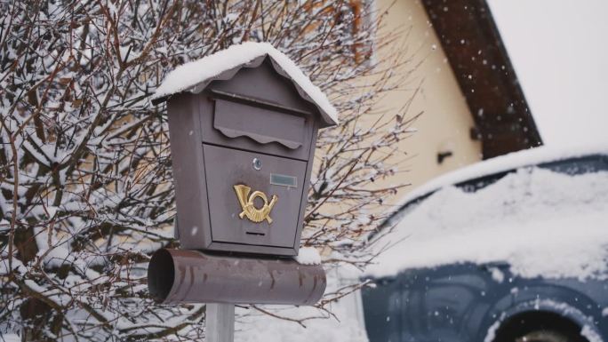 雪落在房子车道上的信箱上