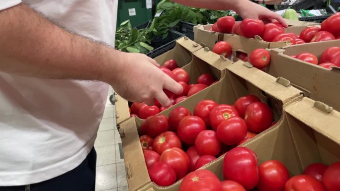 一个男人在蔬菜店买西红柿，在超市选新鲜蔬菜，外卖，网上订购