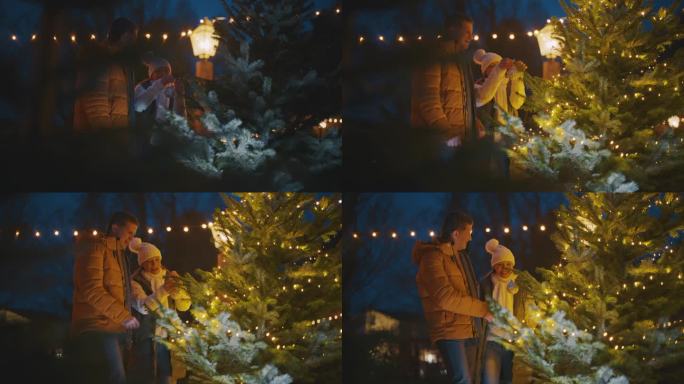 一对夫妇一边在圣诞树上挂装饰品一边跳舞，玩得很开心