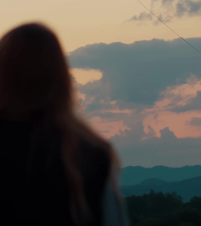 垂直视频村女孩，穿背心的女人在山上俯瞰高山看日落