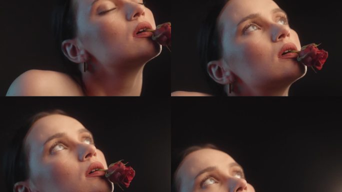 性感的女人用红色的口红和纹身黑色背景工作室拍摄持有与一个单一的红玫瑰在嘴里