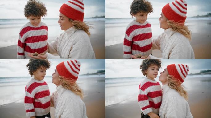 慈祥的母亲在海边亲吻孩子的特写。卷毛的小儿子抱着妈妈