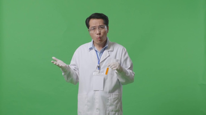 好奇的亚洲男性科学家在试管中使用橙色液体，解释为什么在实验室的绿色屏幕背景下工作令人怀疑