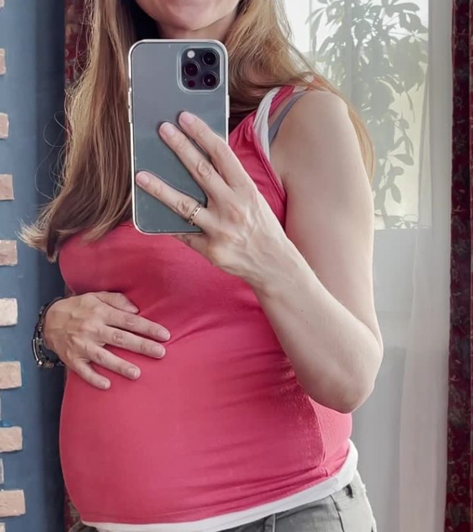 孕妇用智能手机用镜子拍视频自拍