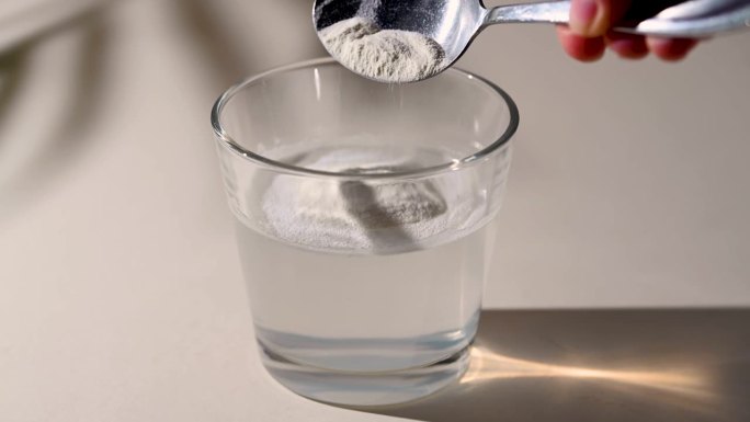 在一杯水中加入胶原蛋白粉。健康食品补充剂