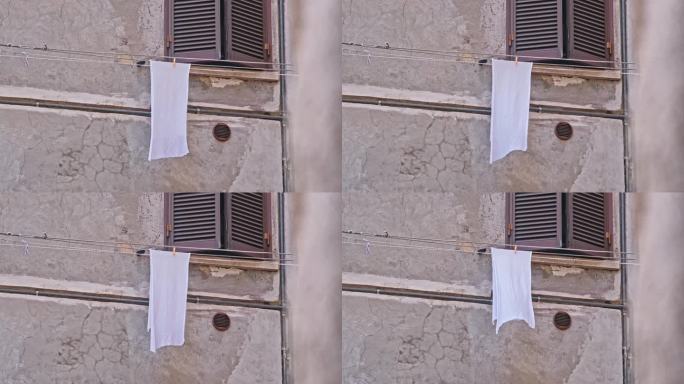 在意大利老城的一条街上，湿的白色棉布、抹布、抹布在晾衣绳上晒衣服
