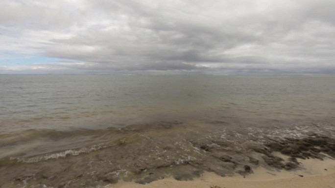 波浪状的海洋盐海水冲击湍流到珊瑚岩岸的水平窗格视图在阴沉的云景白天的时间看着泻湖地平线上的沙滩没有人