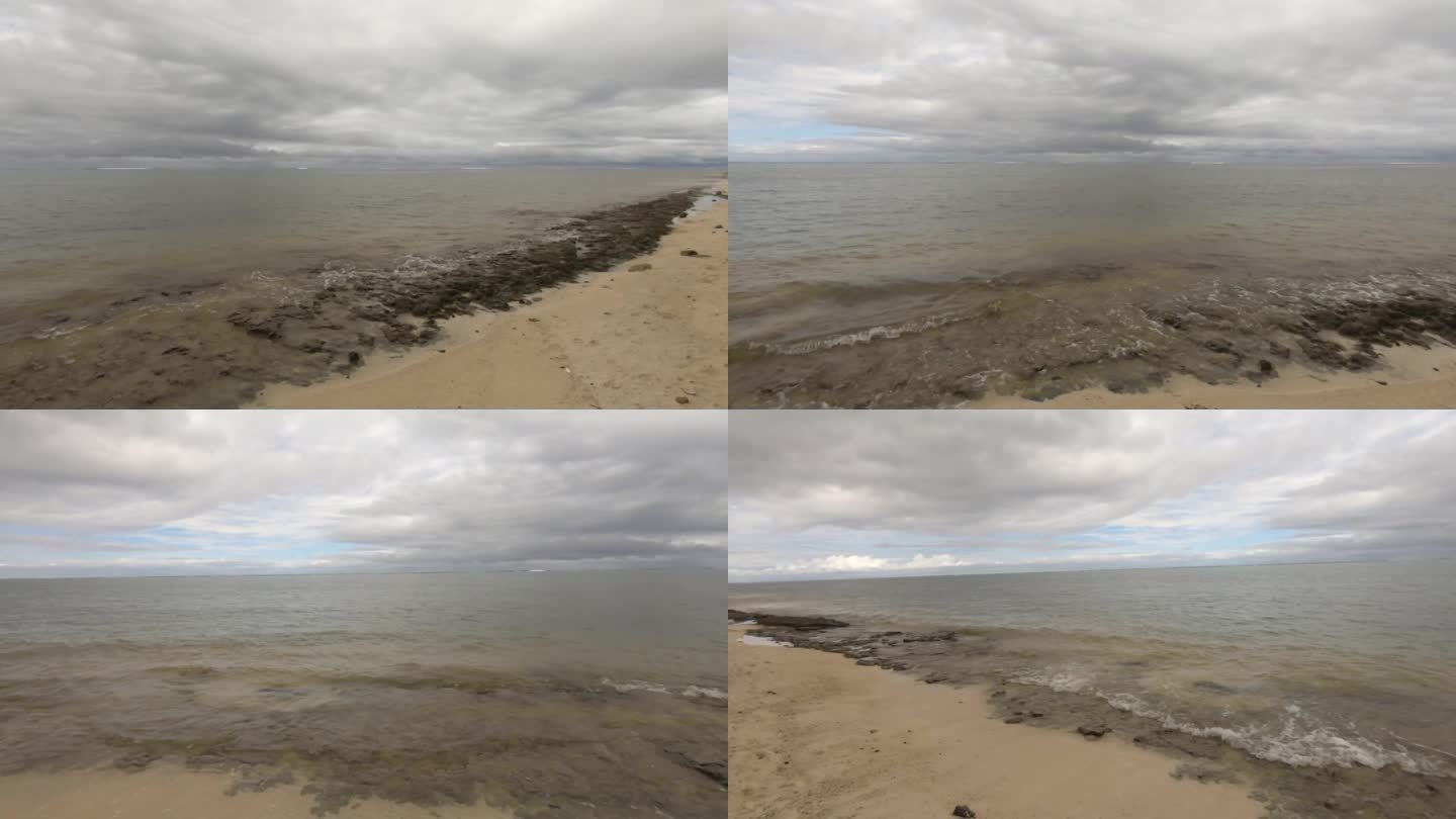 波浪状的海洋盐海水冲击湍流到珊瑚岩岸的水平窗格视图在阴沉的云景白天的时间看着泻湖地平线上的沙滩没有人
