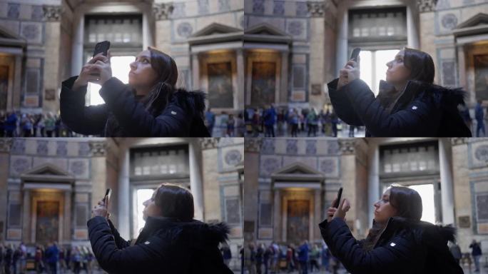 意大利罗马，身穿保暖夹克的年轻西班牙妇女用手机拍摄万神殿内部的照片