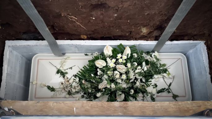 棺材盖上的花被扔进坟墓。