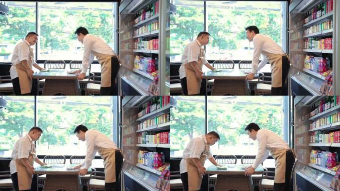 患有唐氏综合症的年轻亚洲男子和他的中年成年同事在餐厅打扫餐桌。残疾超市。