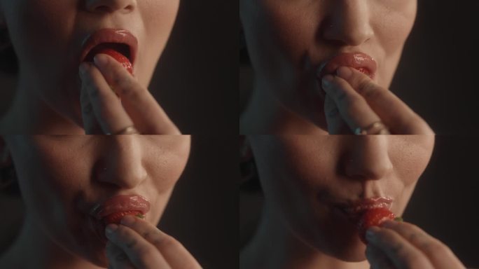 美丽的性感的女人用红色的口红工作室拍摄咬一口甜草莓