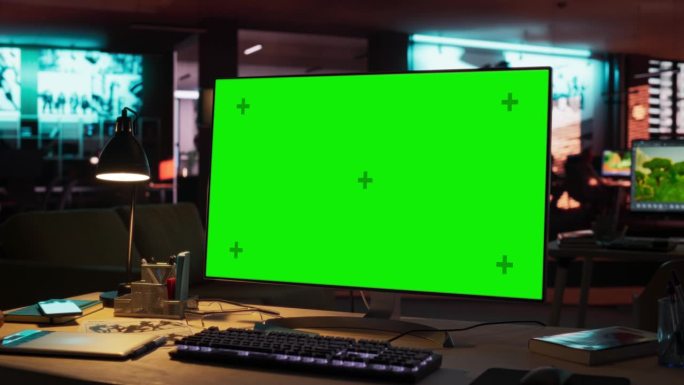 绿屏电脑显示器，立在木桌上，高度可调。游戏开发启动的空装饰创意办公室的色度键显示。放大镜头