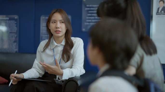 一位老师用平板电脑与亚洲家长讨论国际学校的学费