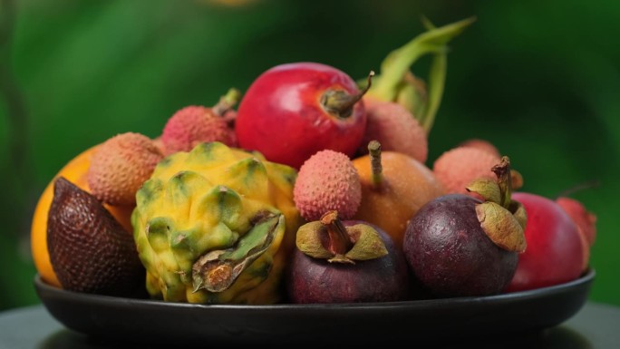 在绿色背景上旋转异国水果(百香果，柽柳，荔枝，Pitahaya, Salak, Granadilla