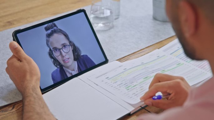 一个女人在笔记本电脑屏幕上和一个在家工作的男人进行视频会议