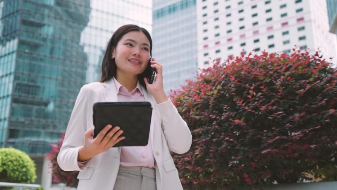 走在香港商业中心中心的女商人用你的手机来协调工作。