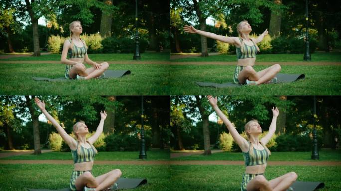 在城市公园外，运动的女人以莲花的姿势坐在瑜伽垫上，举起双手