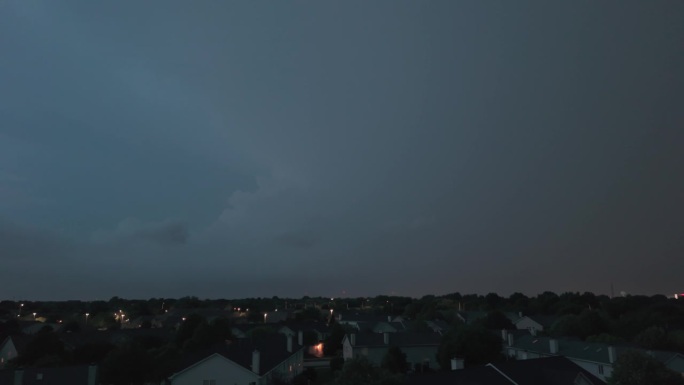 广角航拍的暴风雨云形成在阴暗的天空之前，大雨和闪电在郊区城镇地区。