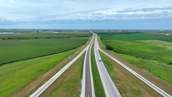 高速公路穿过美国中西部广阔的农田。夏季，卡车和汽车行驶在州际高速公路上，周围环绕着数英里的农田和田野