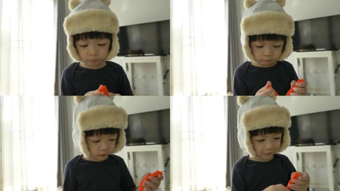 小男孩戴着帽子玩橡皮泥面团和建筑布景，慢动作场景