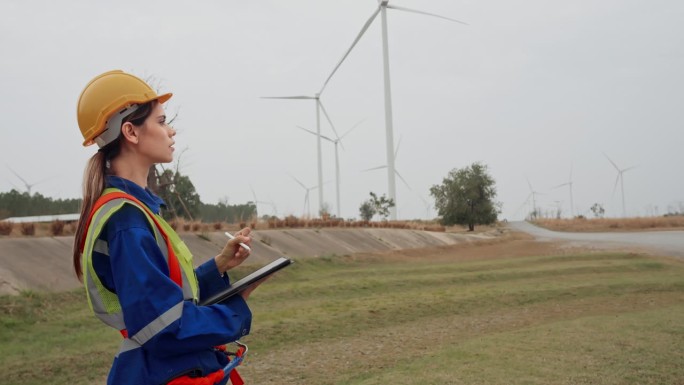 技术人员女队手持平板调查施工区域风力发电机