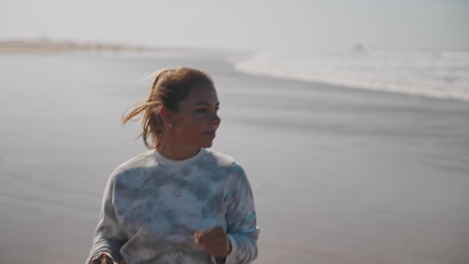 一名女子沿着海岸线在沙滩上慢跑