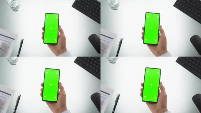一个人拿着智能手机的自上而下的视图，模拟绿色屏幕Chromakey显示与运动跟踪占位符。带无线电脑设