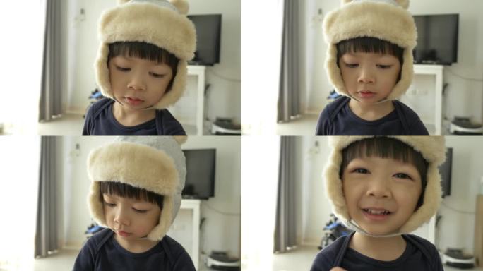 快乐的小男孩戴着帽子在家里玩耍和微笑，慢动作的场景