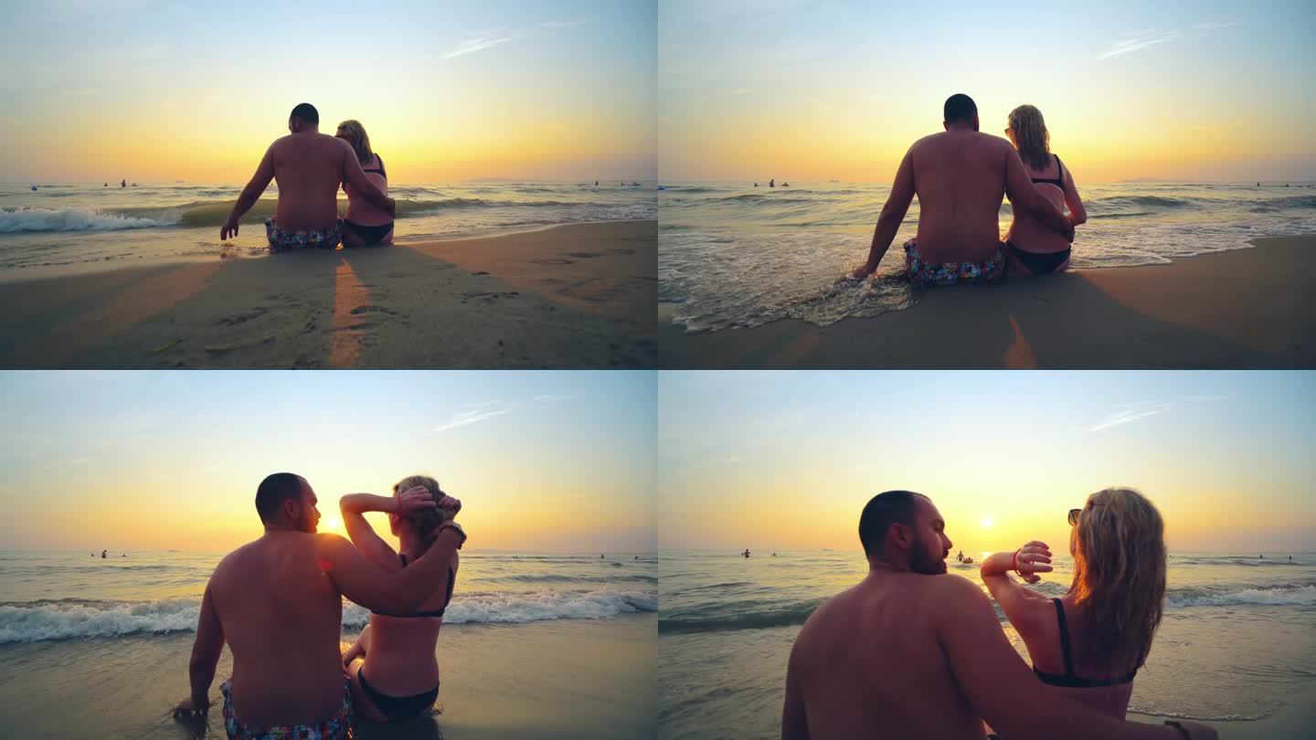 夏天旅行、度假时，一对相爱的情侣在海滩上一起看日落。剪影从后面坐着拥抱享受日落，日出的海洋上的热带目