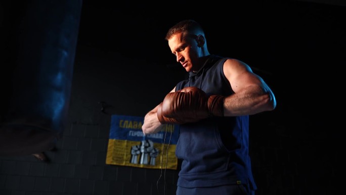 男拳击手在健身房戴上拳击手套。