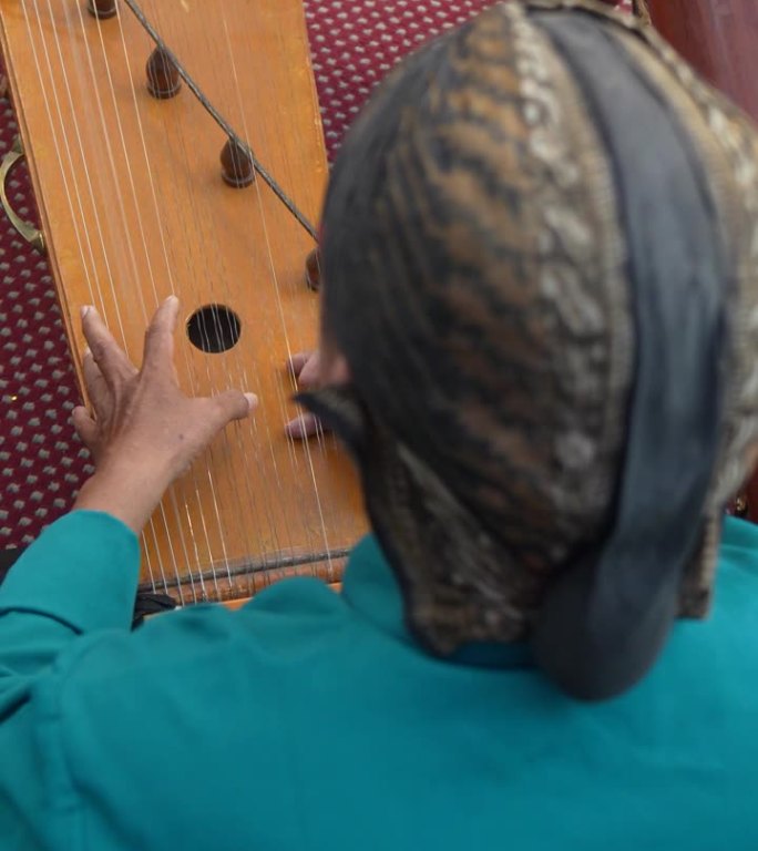 年长的成年人戴着布兰康(一种西爪哇的传统帽子)，穿着传统服装，弹着竖琴或古筝