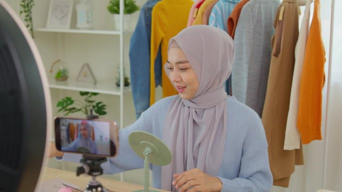 美丽的穆斯林女孩在社交媒体平台上直播故事自拍在家化妆示范。穆斯林女博主教化妆用智能手机录制视频。