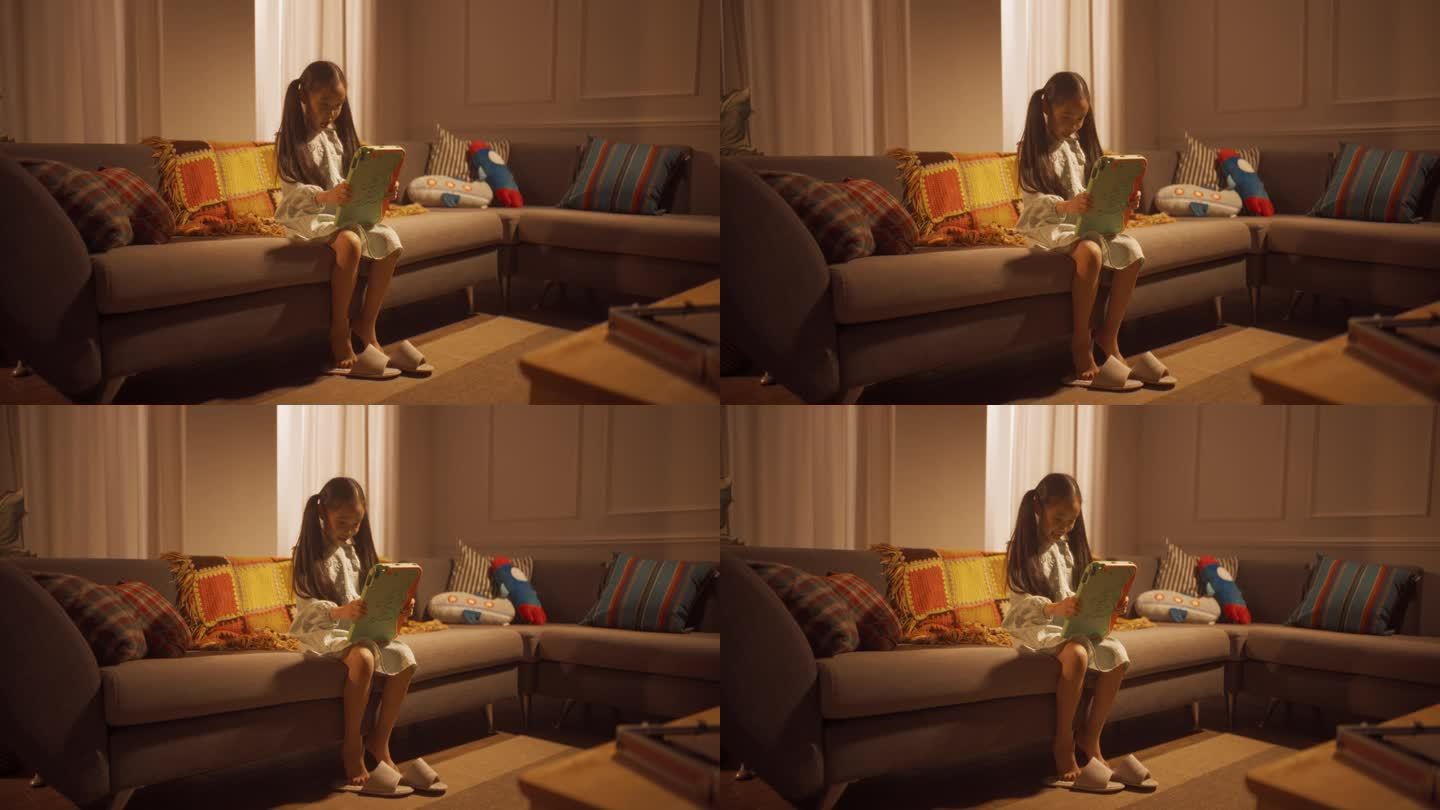 一个韩国小女孩坐在客厅的沙发上，用平板电脑玩电子游戏的广角照片。活跃的女性儿童使用互动媒体学习