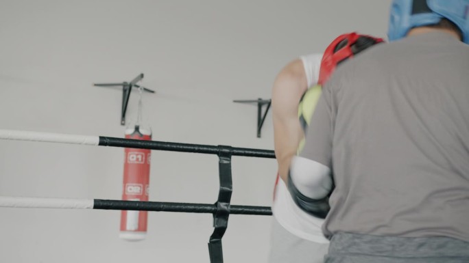 戴着头盔和手套的职业拳击手在现代体育馆里训练出拳