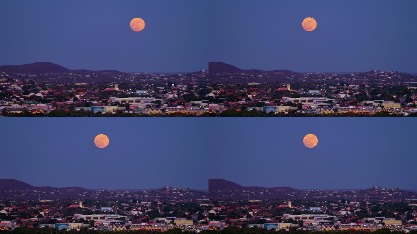 黄昏时分，潘横跨库拉索岛的威廉斯塔德市，罕见的蓝色超级月亮在紫色的天空下升起