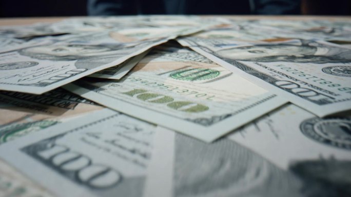 美元钞票堆积在一起。美国纸币散落在桌子上。
