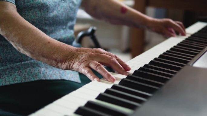 一位退休老妇人在家里弹钢琴的特写镜头