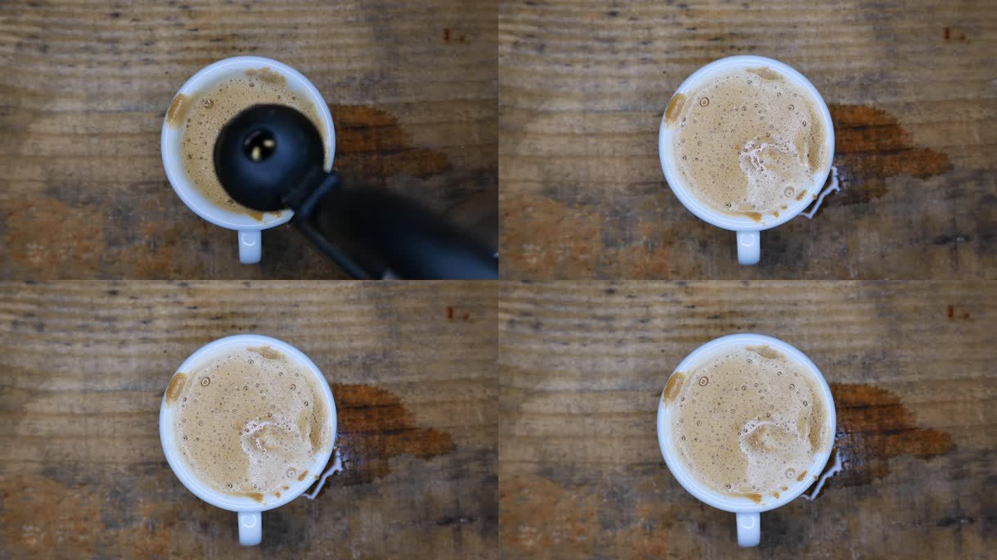 视角:桌上一个冒着热气的咖啡杯，俯视图。将沸水倒在奶油咖啡上的人。咖啡杯中升起的蒸汽。桌上有一杯咖啡