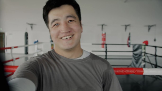 快乐的亚洲运动员在健身房进行在线视频通话，看着镜头，穿着制服