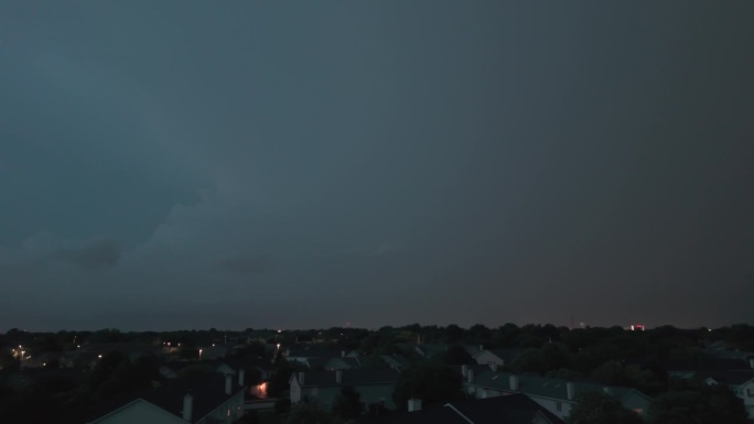 广角无人机拍摄的暴风雨云形成在阴暗的天空之前，大雨和闪电在郊区城镇地区。