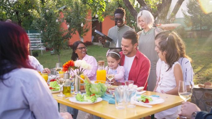 多种族多代家庭在花园享用家庭午餐